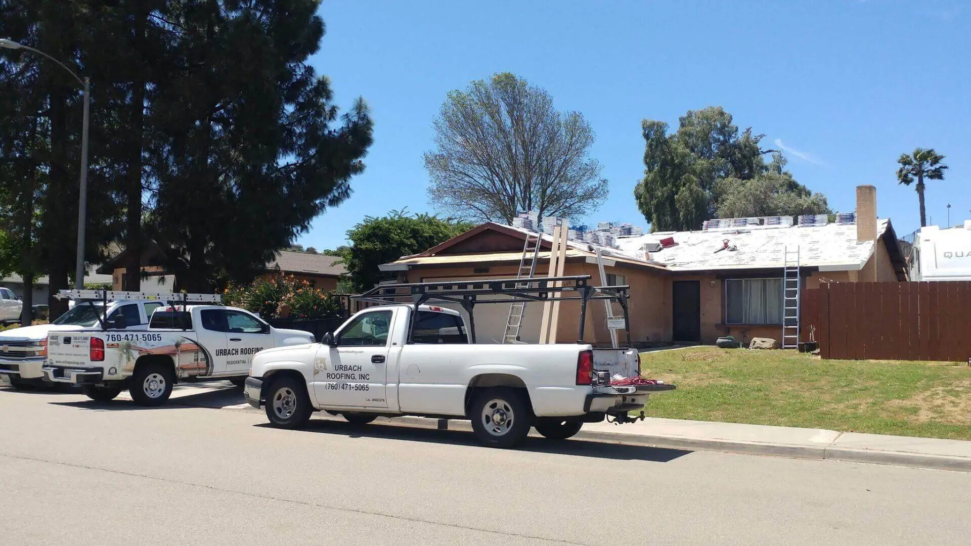 Trucks parked near house under roof repair.