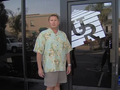 Man in floral shirt outside a building.