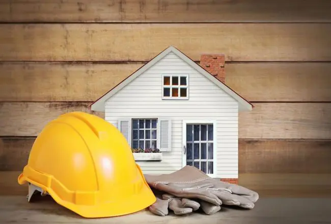 Hard hat and gloves by small house.
