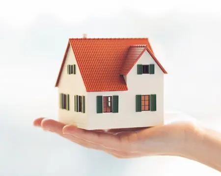 Hand holding miniature model house.
