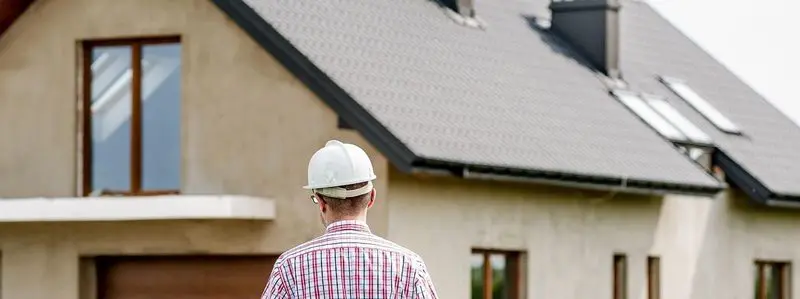 Builder inspecting house construction with helmet.