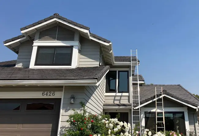 House exterior with ladders under clear sky.