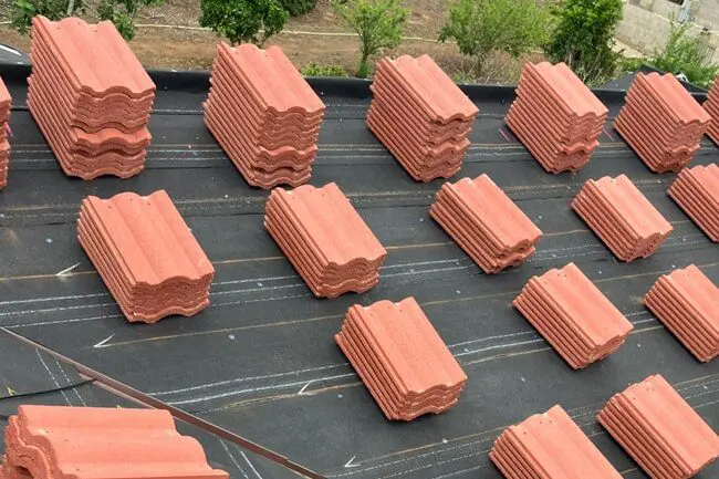 Stacks of red roof tiles on roof.