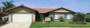 A house with grass and bushes in front of it.