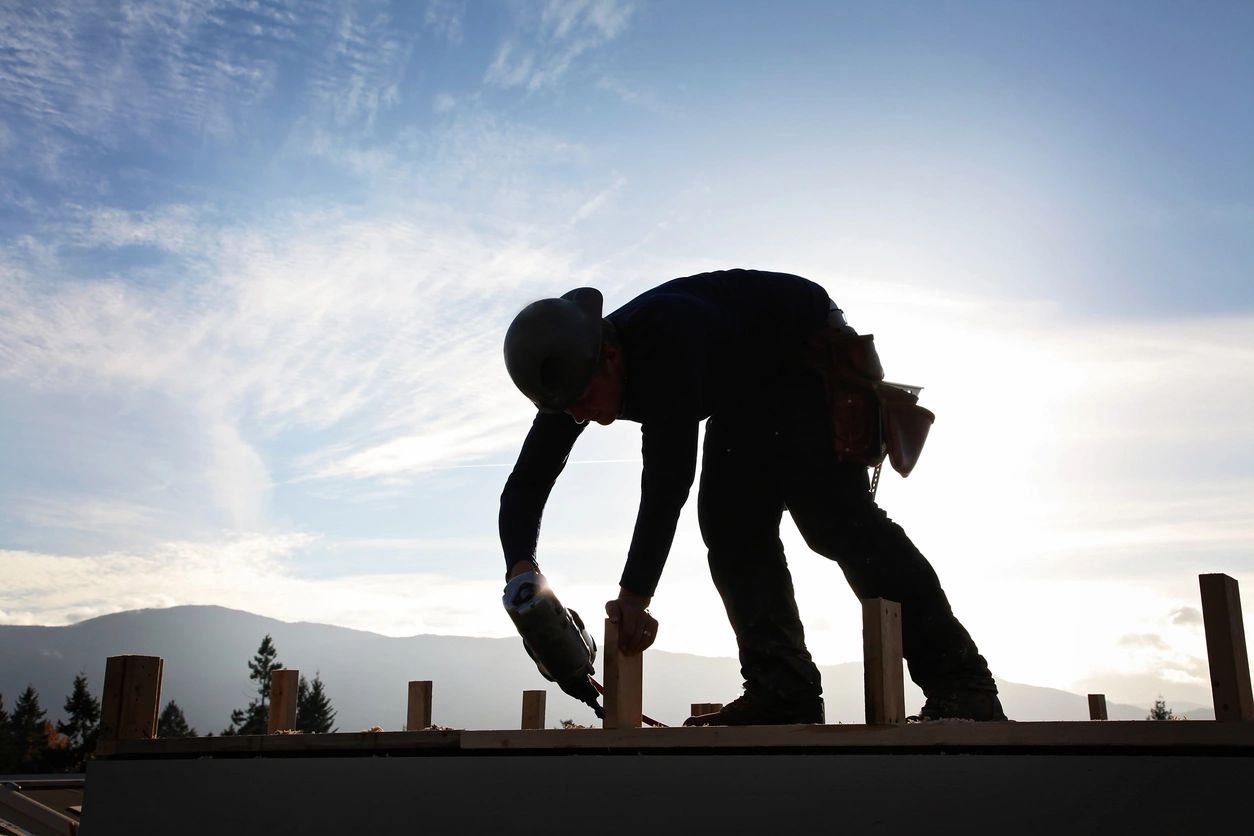 A man in black shirt and white helmet on top of building.