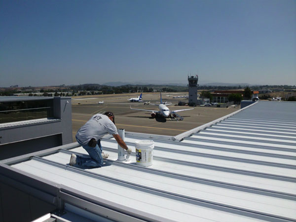 A man painting a roof at an airport