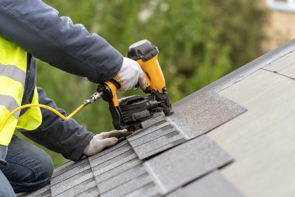 A person is using an electric nail gun to attach shingles.